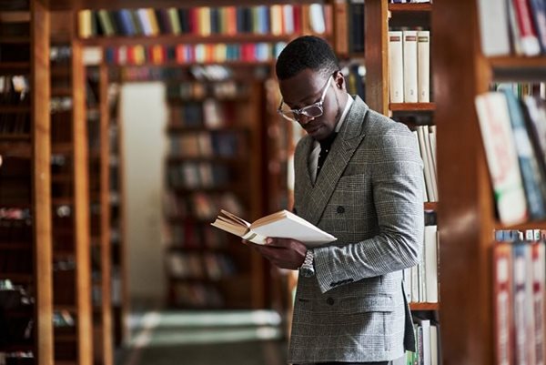 African American man reading a book in a library