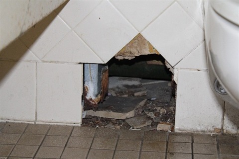 An image of a hole in the wall of a bathroom